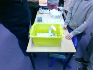 A photo of a box of materials sitting on a wooden desk, ready for a Science experiment to be conducted using them by the class teacher.