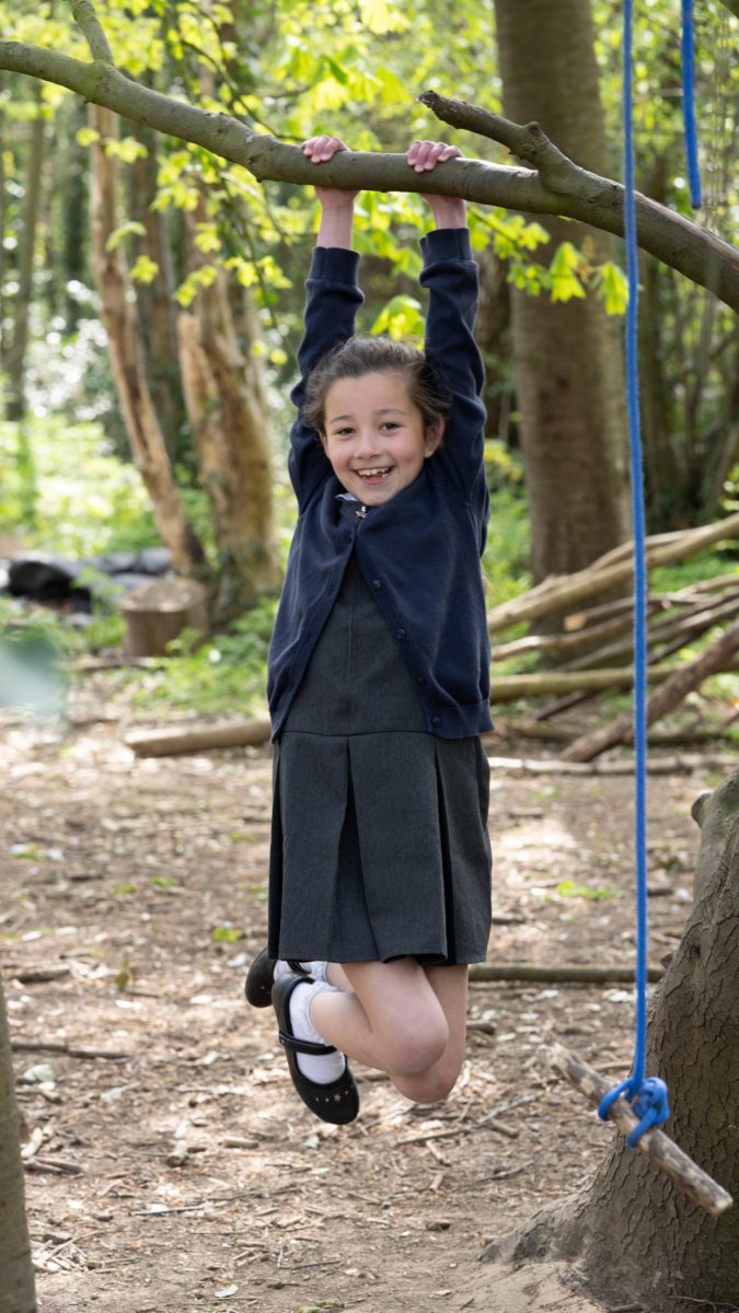 A student hanging off a tree branch